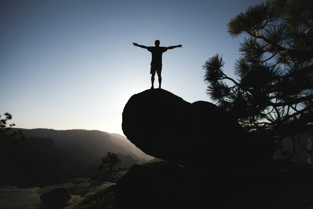 A person standing triumphantly on a mountaintop at sunrise, symbolizing freedom, clarity, and expanded awareness.